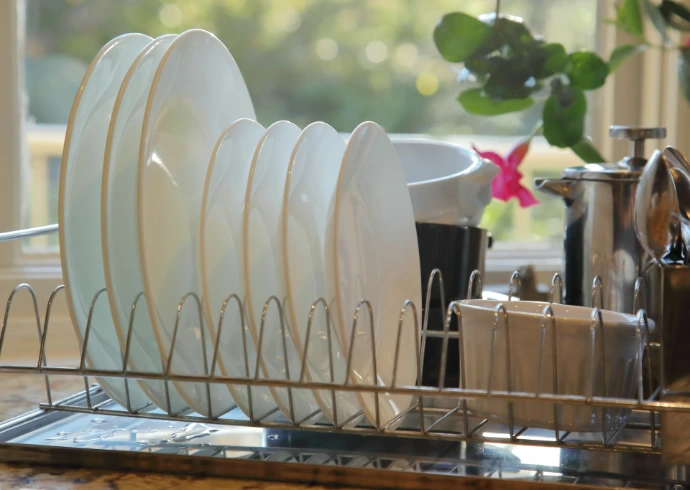 Clean white plates drying in a metal dish rack